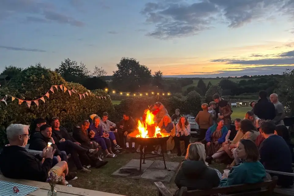 Wedding guests gathered around a firepit at sunset